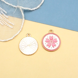 Macro shot of pink enamel cherry blossom pendants with golden metal radiating texture