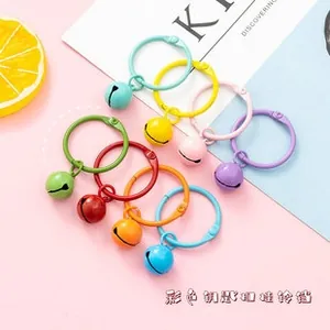 Flat lay of colorful macaron metal keychains with mini bells and jump rings on pastel background
