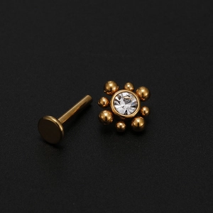 Macro view of gold titanium labret post with cluster zircon top on black background