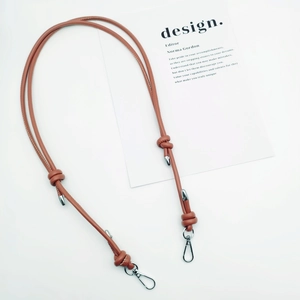 Detail of adjustable brown leather shoulder strap with knot design and silver metal hooks