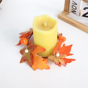 Close-up of fall maple leaf and pumpkin wreath with warm yellow LED candle lamp