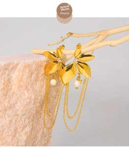 Macro detail of gold flower tassel earrings with white pearl on minimalist stone props
