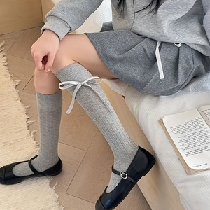 Close-up of grey vertical striped calf socks with cute white ribbon bow detail
