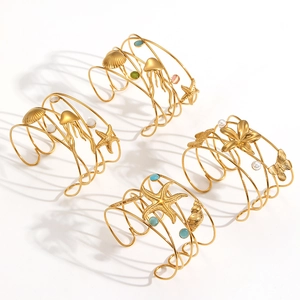 Golden sea star and jellyfish open bracelets with pearls on a clean white background