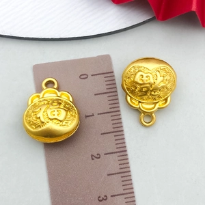 Detail shot of two gold Fu character pendants next to a ruler measuring 1.5cm in size