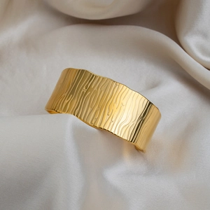 Détail d'un bracelet jonc en acier inoxydable doré à l'or 18K avec texture écorce