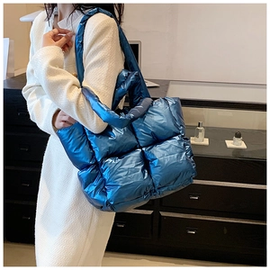 Metallic blue quilted tote bag with padded puffer design and wide shoulder strap