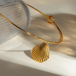 Detailed view of a golden stainless steel shell pendant necklace with beach style design