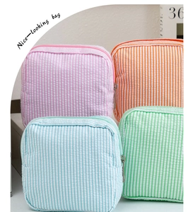 Détail macro de pochettes à maquillage en seersucker rayé rose, bleu et vert pastel