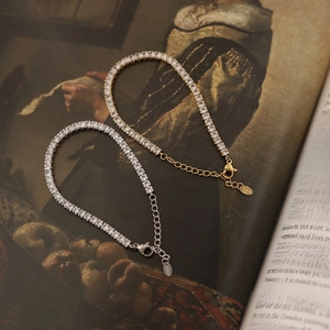 Macro detail of gold and silver square zircon tennis bracelets on vintage art book pages