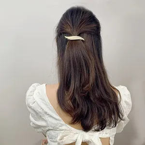 Close-up of golden leaf hair clip used in a half-up hairstyle on model back view