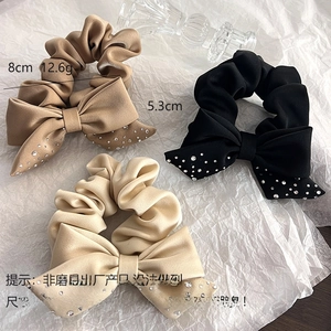 Detailed view of suede bow hair ties in black, khaki and beige with sparkling rhinestones