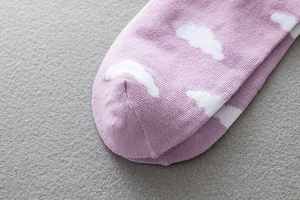 Close-up of violet knit socks featuring white cloud pattern and reinforced toe seam