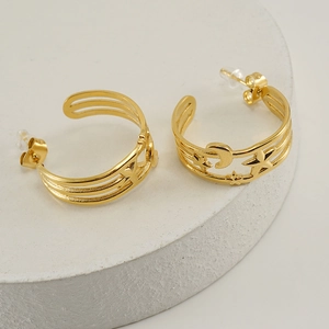 Gold stainless steel star and moon C-shape hoop earrings on a white stone display