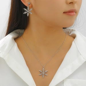 Detail of elegant snowflake necklace and hook earrings set with sparkling zircons