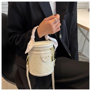 White cylinder bucket bag with embossed pattern and pink silk scarf wrap on the handle