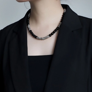 Close-up of black agate beads and silver metal rings necklace on a male model neck