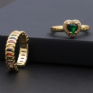Détail d'une bague dorée avec cœur émeraude, gravure LOVE et gemmes colorées