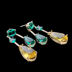 Elegant gold drop earrings with teardrop green and yellow faceted gemstones on black back