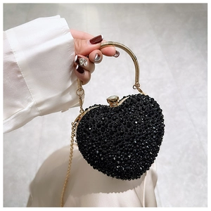 Close-up of heart-shaped evening bag with black rhinestones and golden metal ring handle