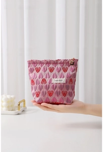 Detailed pink canvas cosmetic bag with red heart embroidery and golden flower zipper pull