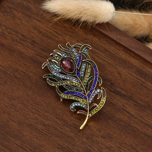 Macro detail of retro peacock feather brooch with colorful zircons and golden base