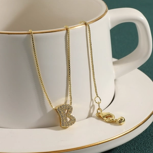 Detailed close-up of gold box chain necklace featuring a sparkling letter B pendant with zircons