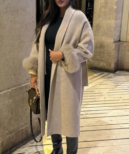 Détail d'un manteau en laine beige avec poignets en fourrure et ceinture nouée à la taille