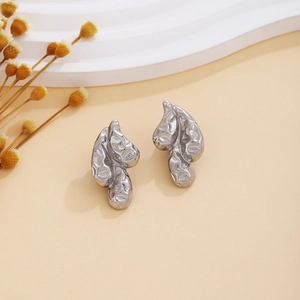 Close-up of silver earrings with molten lava texture and fluid organic triangular shape