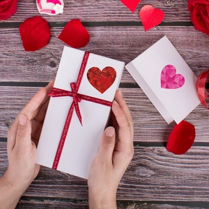 Macro view of white gift box with glitter heart sticker and printed red silk ribbon