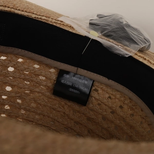 Macro view showing the internal care label and sweatband of a hand-woven raffia straw hat