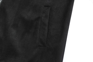 Detailed view of black faux suede jacket featuring a vertical pocket and metal zipper detail