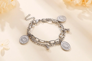 Detail of silver double-layer chain bracelet with sun and moon engraved oval pendants