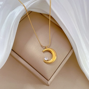 Macro shot of gold crescent moon pendant with zircon on a warm silk fabric display