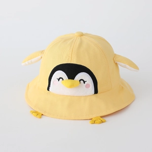 Détail d'un chapeau bob en coton jaune avec un pingouin 3D mignon avec ailes et pieds