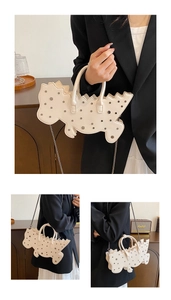 Detail of cream white dinosaur bag featuring metal studs and elegant chain strap