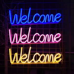 Détails des enseignes néon Welcome en bleu, rose et jaune sur support mural