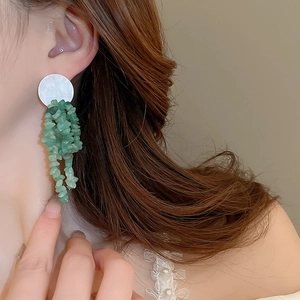 Macro view of green stone tassel earrings worn by a model showcasing elegant drape