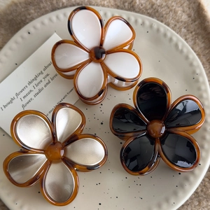Detailed set of three vintage amber resin flower hair claws on a stylish beige plate