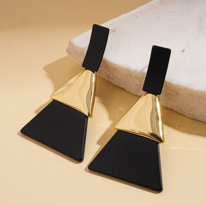 Détails de boucles d'oreilles géométriques en acrylique noir et métal doré sur pierre