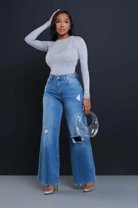 Detail of high waisted distressed wide leg jeans with ripped knees and raw hem edges