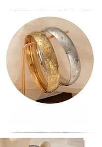Close-up of engraved floral patterns and zircon accents on gold and silver bracelets