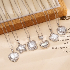Minimalist silver necklaces with assorted white clover and heart pearl pendants on a wood tray