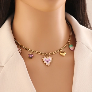 Collana a cuore dorata alla moda con ciondoli rosa e fragola indossata da una modella