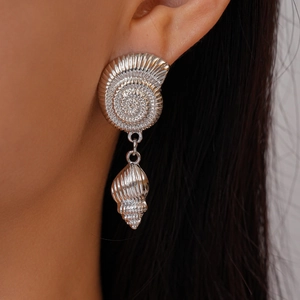Detailed close-up of chunky silver shell earrings with nautilus and conch drop design