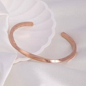 Detailed view of rose gold C-shaped cuff bracelet with engraved Roman numerals on silk