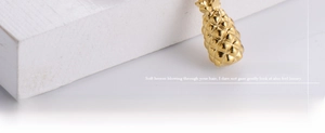 Detailed macro view of gold pineapple pendant featuring intricate grid-patterned engraving