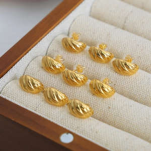 Gold-plated C-shaped twist stud earrings displayed in a luxury wooden jewelry box