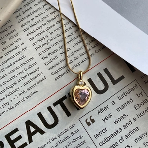 Detail of a gold titanium necklace featuring a pink heart pendant with micro zircon stones