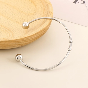 Close-up of a silver minimalist open cuff bracelet with spherical beads on white background